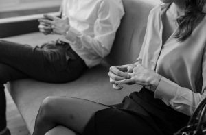 Symbolbild für Trennungscoaching: Eine Frau spielt nachdenklich mit ihrem Ehering während eines Beratungsgesprächs auf dem Sofa.
