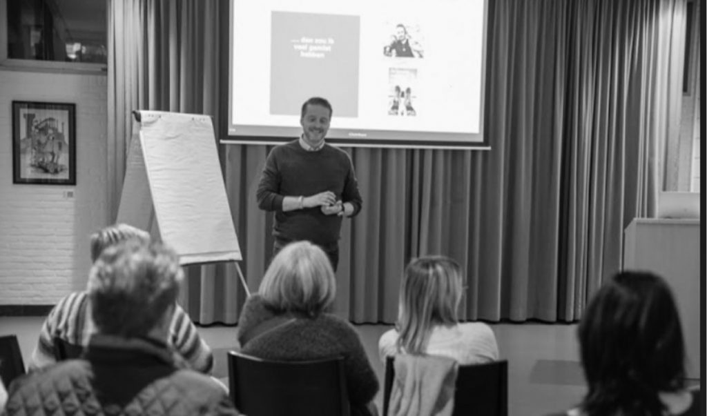 Bjorn Kiggen lächelt während eines Vortrags über Resilienz vor einer Gruppe von Zuhörern.