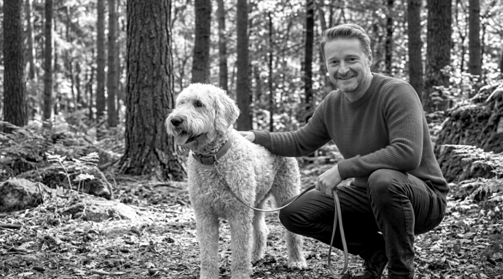 Mental Health Experte und Autor im Wald mit Hund Ludwig, Thema Resilienz und Erholung in der Natur.