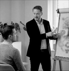 Mental Health Coach im persönlichen Gespräch mit einem Klienten am Flipchart zur Erarbeitung individueller Resilienz-Strategien.